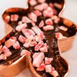 Filling cookie cutter with fudge mixture to prepare Christmas cookie-cutter peppermint fudge.